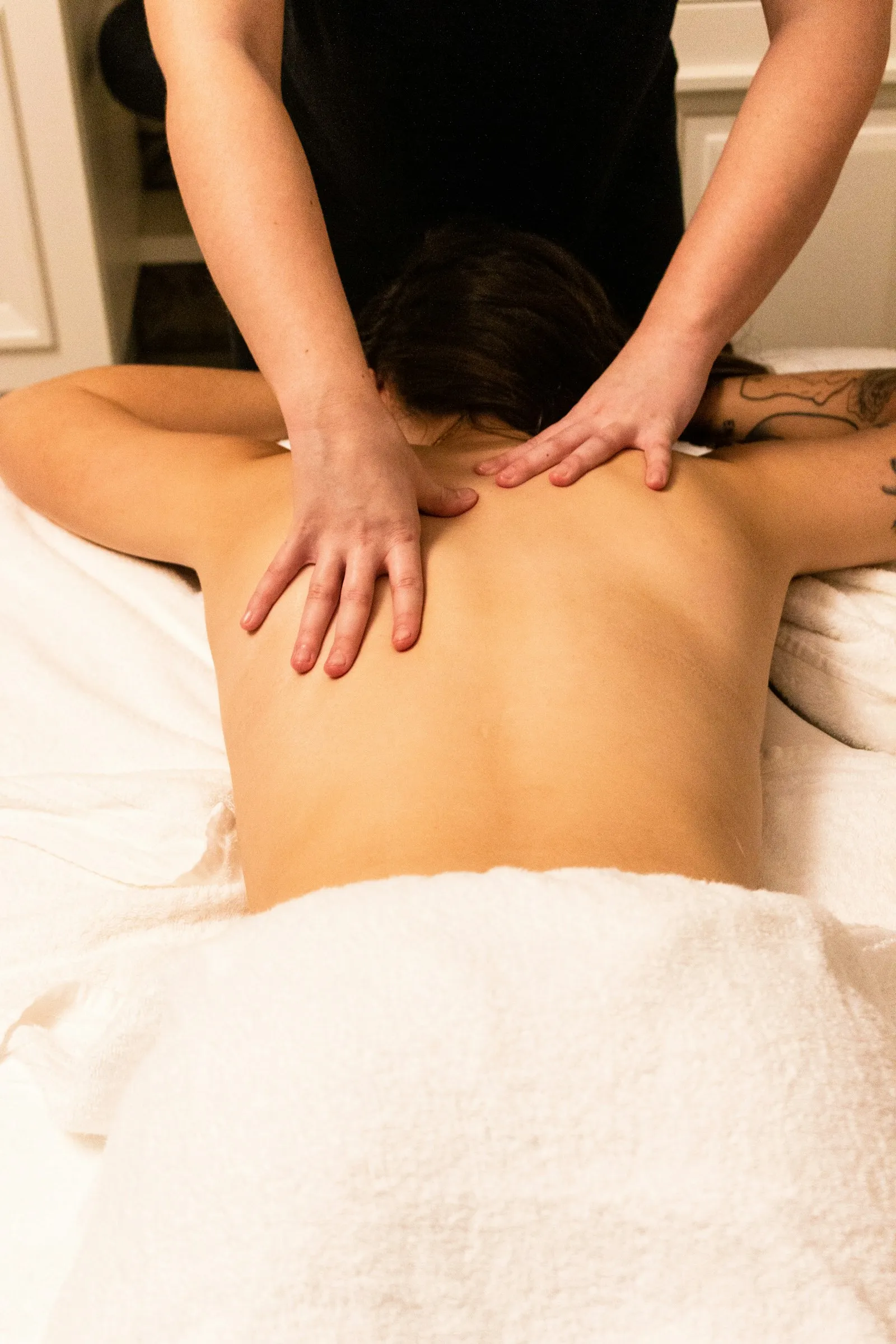 Nahaufnahme einer Rückenmassage in einem Spa, warmes Licht, ruhige Atmosphäre.