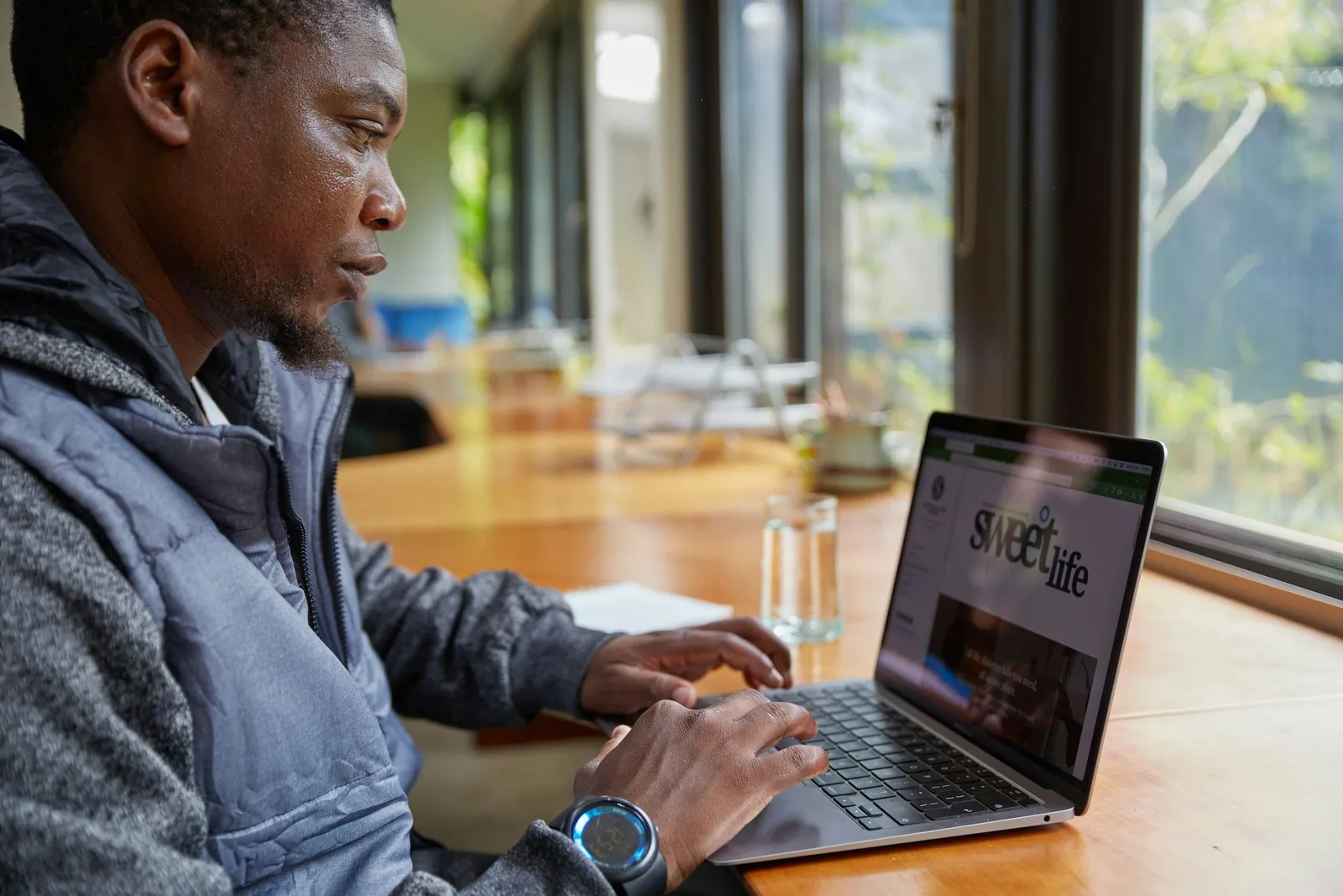 Mann arbeitet am Laptop in der Nähe eines hellen Fensters, ruhige fokussierte Arbeitsatmosphäre im Tageslicht