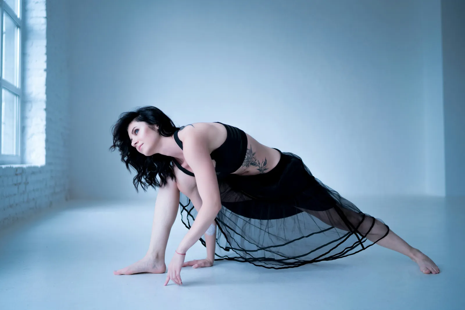 Frau in tiefem Ausfallschritt in einem hellen, minimalistischen Studio mit weißen Wänden.